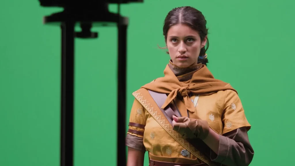 Actress Anya Chalotra, dressed as Haroona, in front of a green screen.